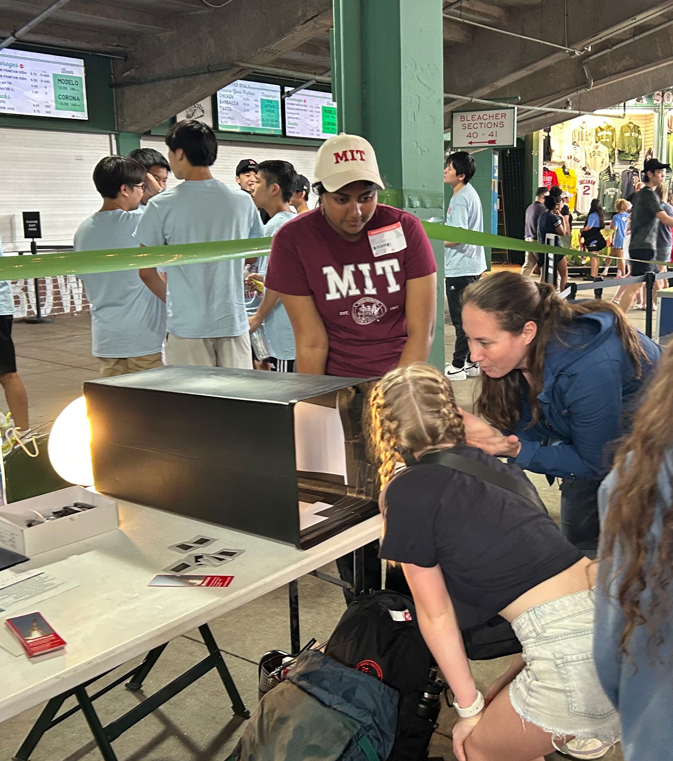 Two female researchers from MIT demonstrate for a middle school student how polarized light filters work.