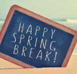 A chalkboard in the sand reads "Happy Spring Break" and the ocean is seen in the background