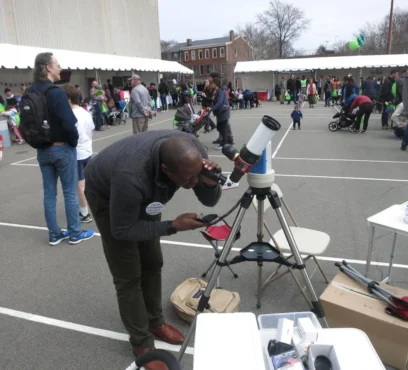 A man looks through a telescope in the daytime.
