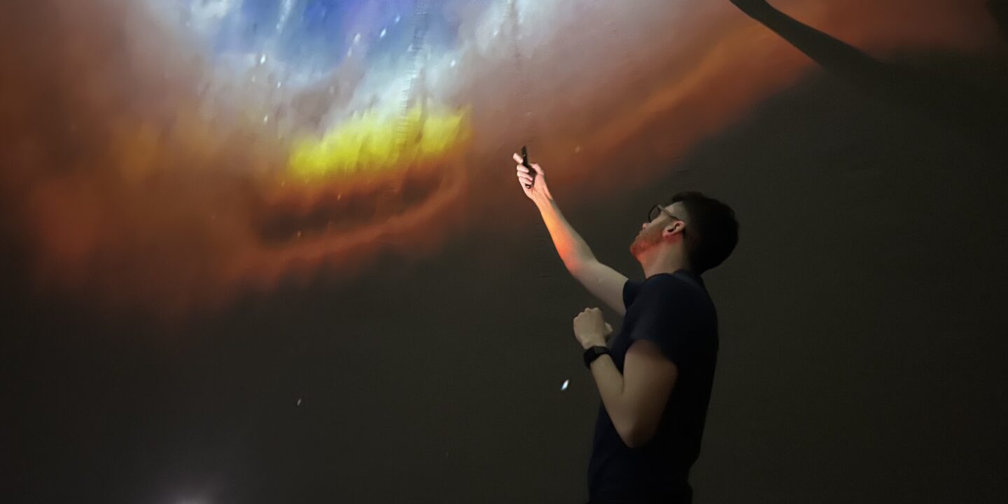 a researcher points out colorful layers in a cloud of expanding gas